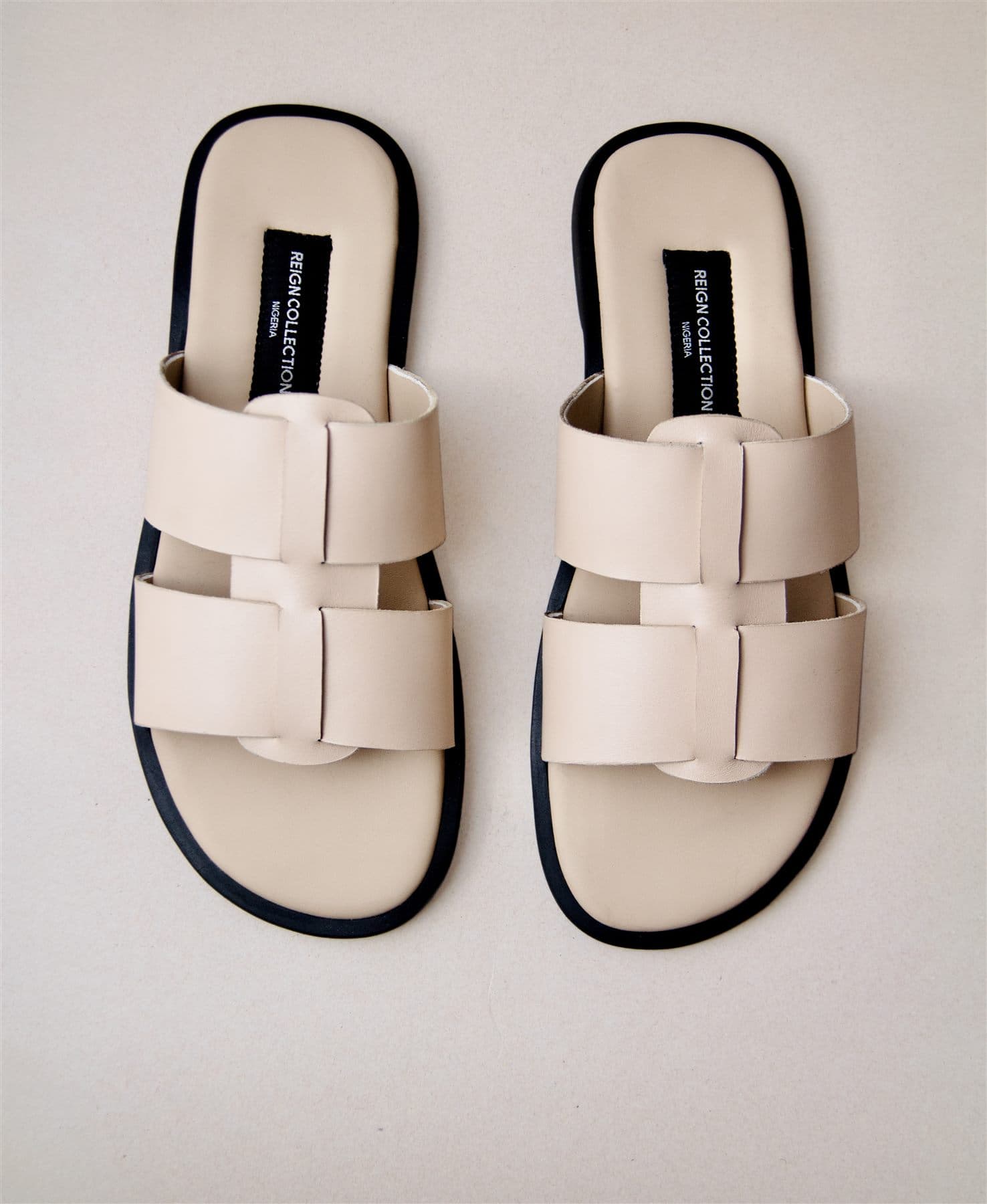 A pair of nude leather slides, hand-finished in Lagos